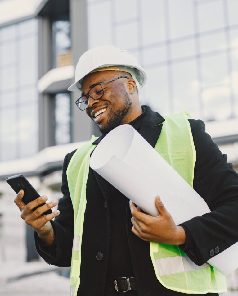 Young black race man with blueprint stading near glass building. Talking by phone.
